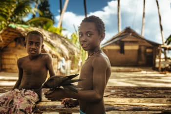 Boys hold bird on village ground