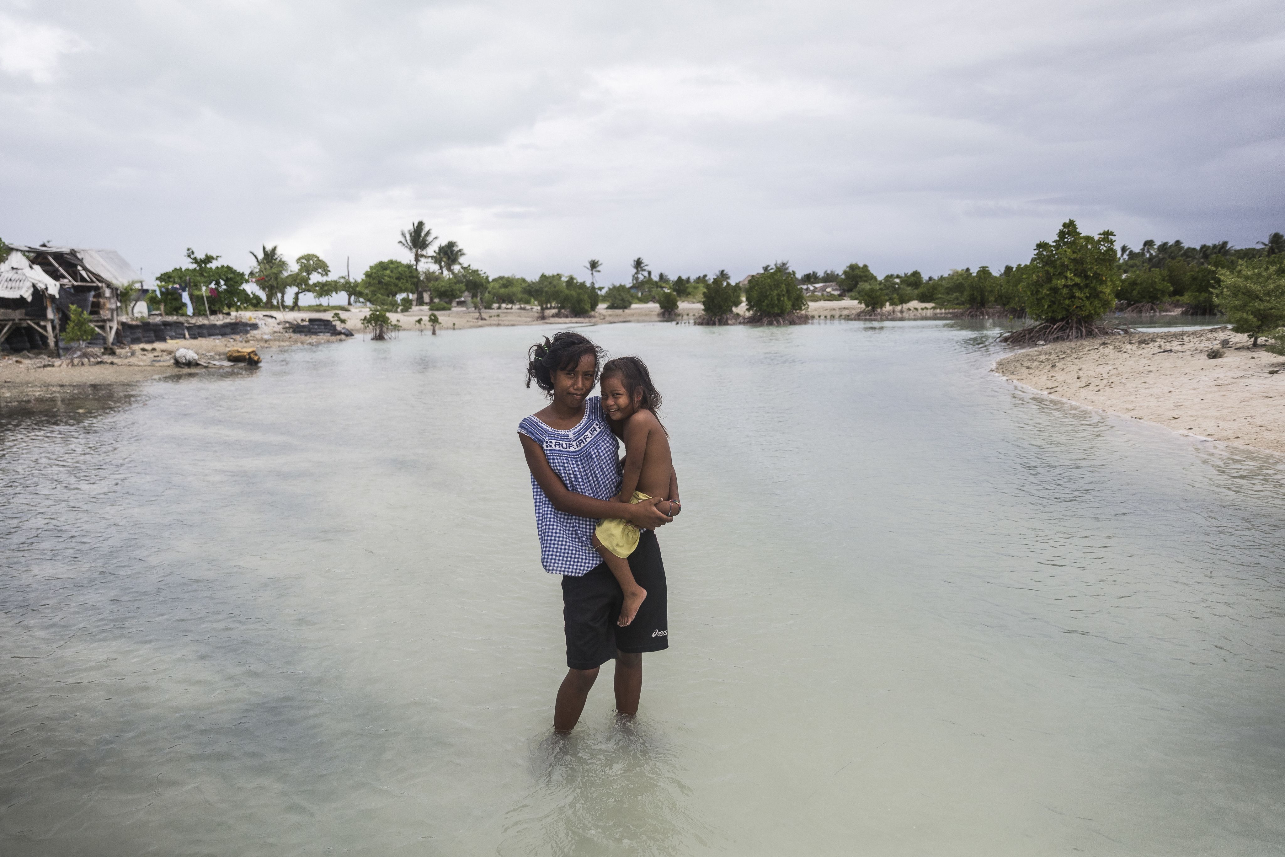 Kiribati, 2016  Taronga, 16, holds her two-year-old sister Teaborenga while standing in a flooded area in the village