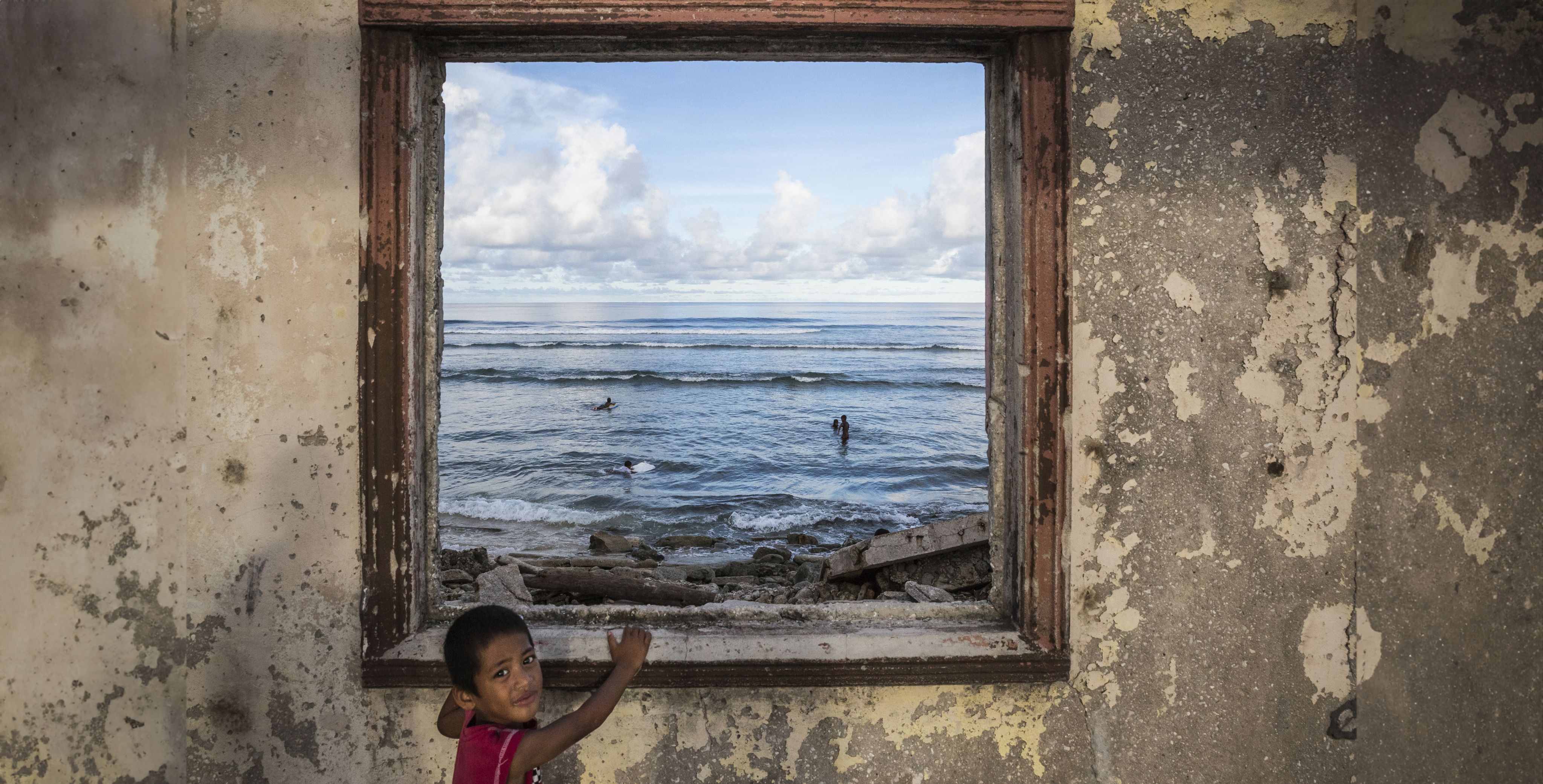 Boy at rustic window overlooking Pacific seas 