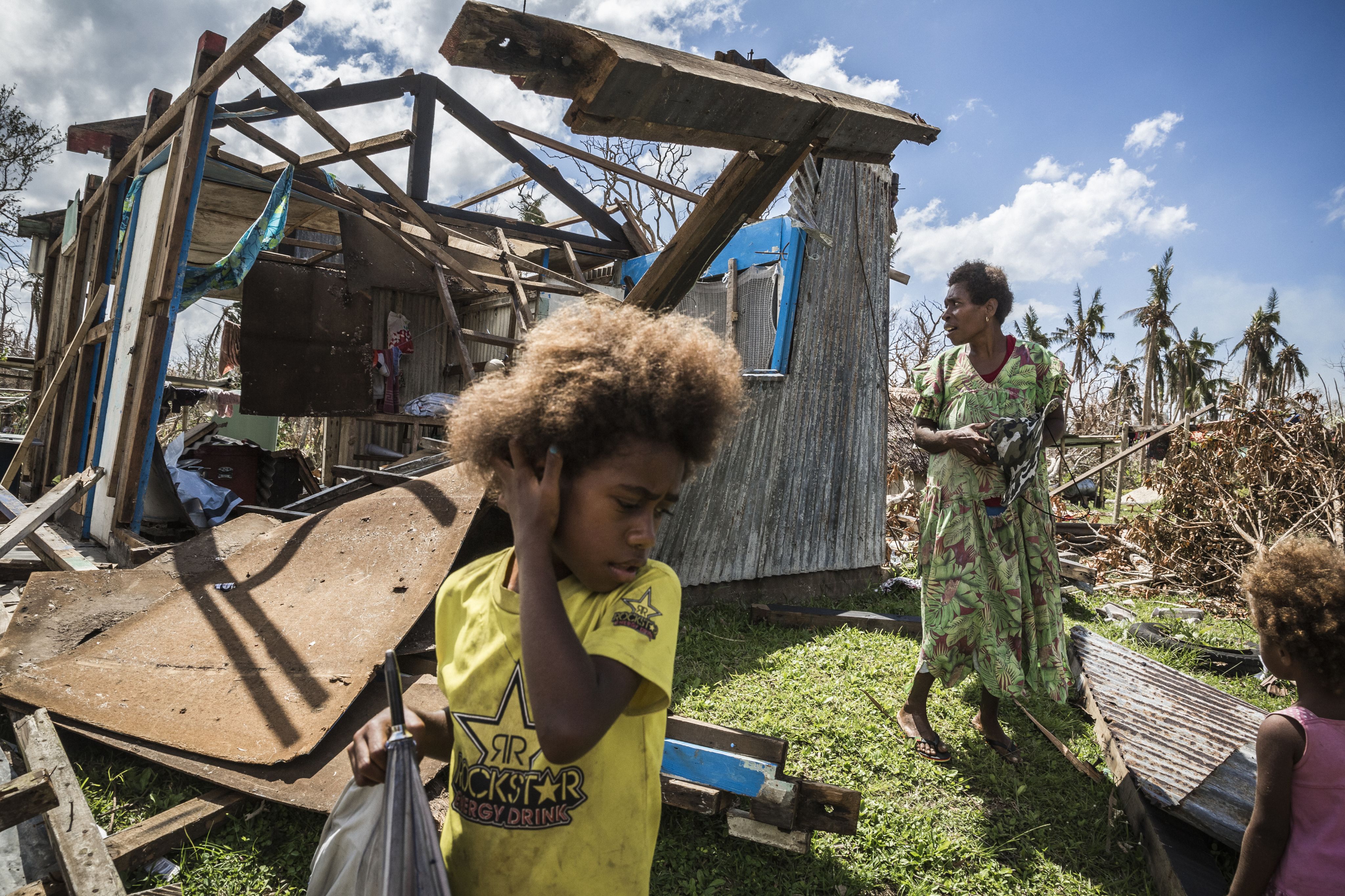 Mother and child around storm-devastated house